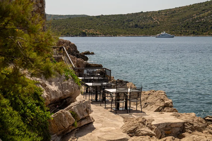 Stolovi restorana na kamenoj obali uz mirno more