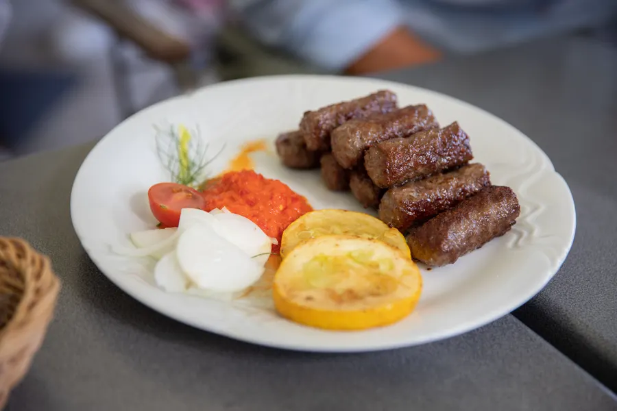 Ćevapi s roštilja na tanjuru, uz luk i ajvar